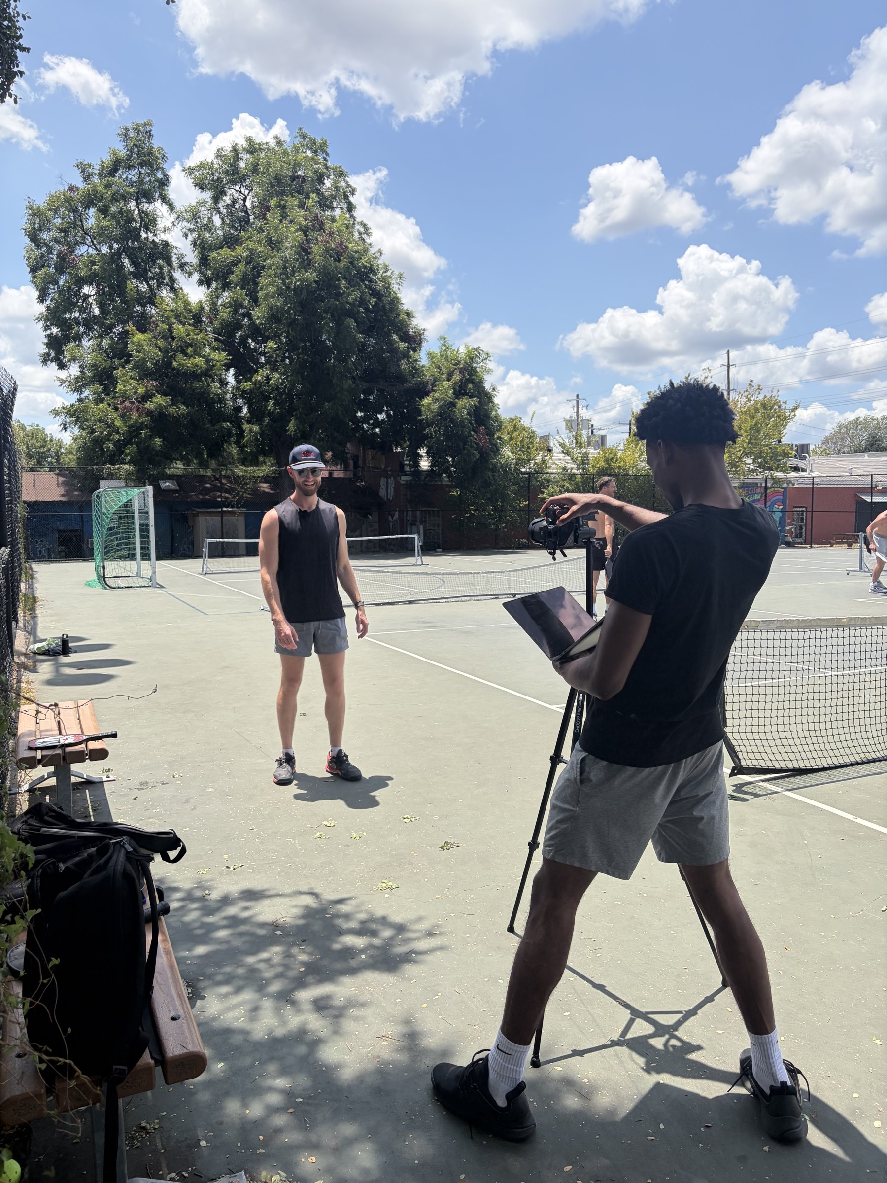 Dom filming a client on a tennis court